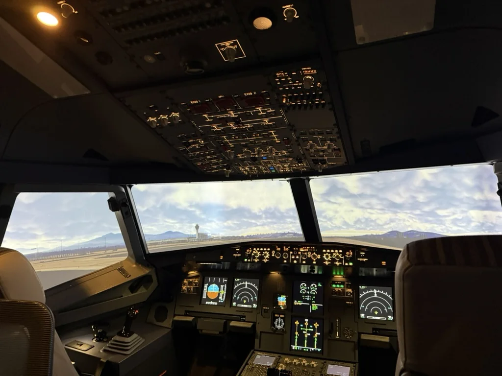 SkyDynamics A320 FNPT II flight deck with an airport in daylight in the visual system